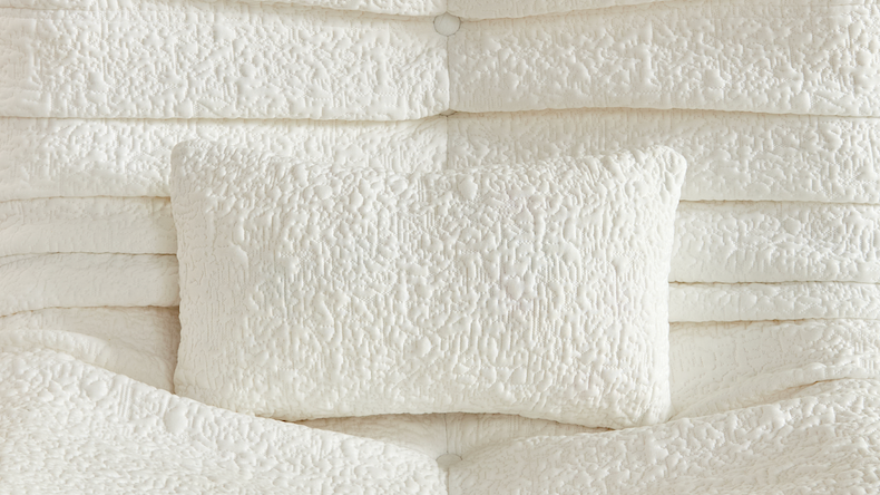 Close-up of a chenille textured white pillows on a white bean bag chair background