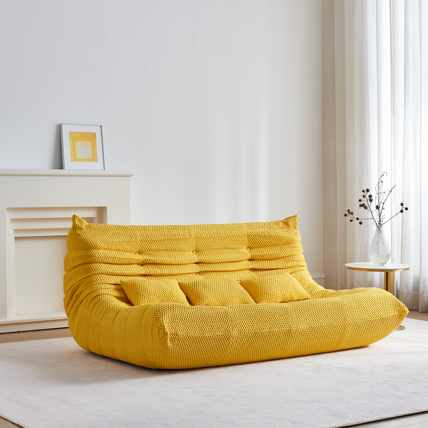 Yellow bean bag floor sofa three seater in a minimalistic room with white walls and light wood flooring.