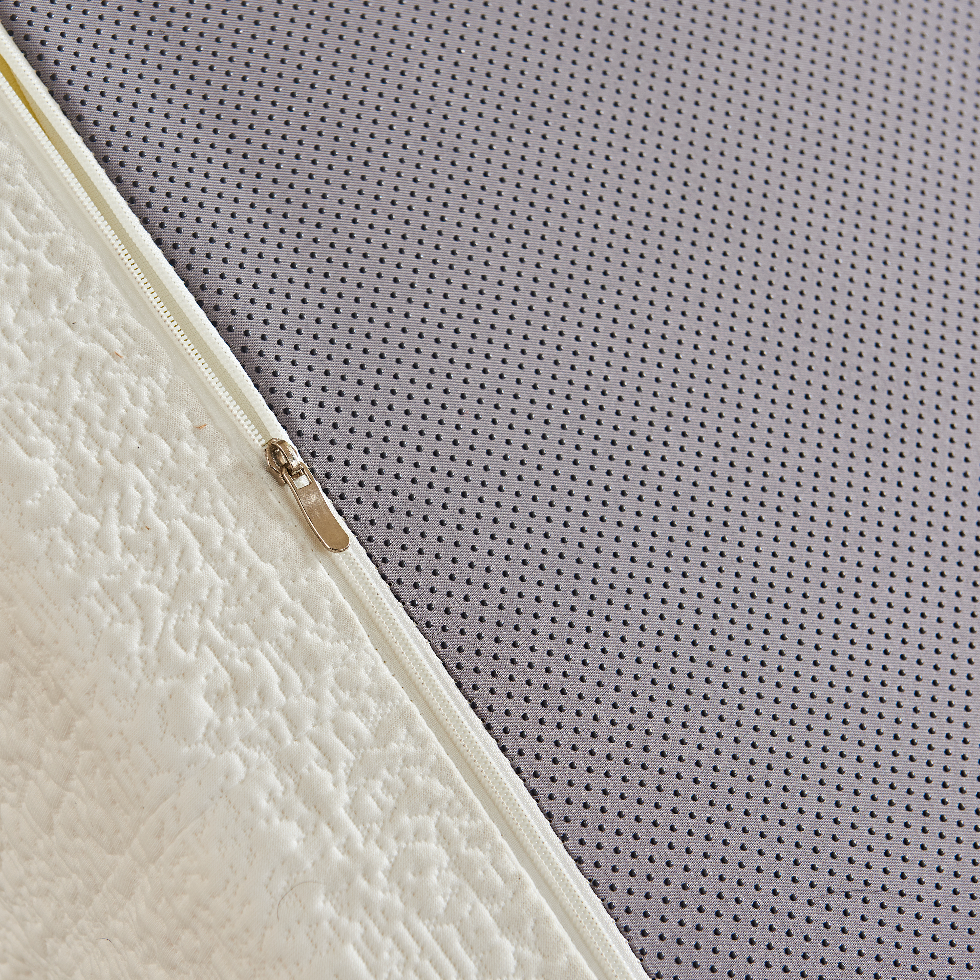 Close-up of a textured mattress corner with a gray non-slippery dots surface.