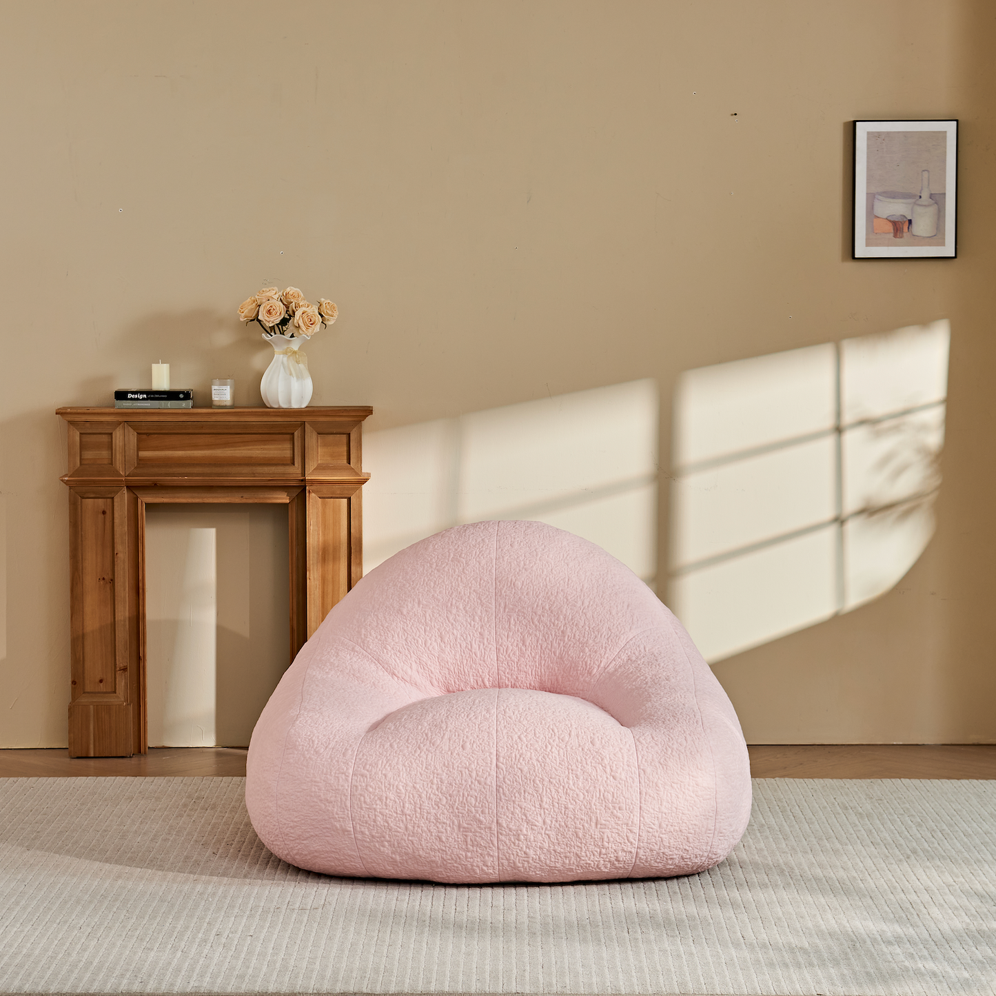 Zoovee's Chenille Pink oversized bean bag chair in a room with a wooden fireplace and framed picture on the wall.
