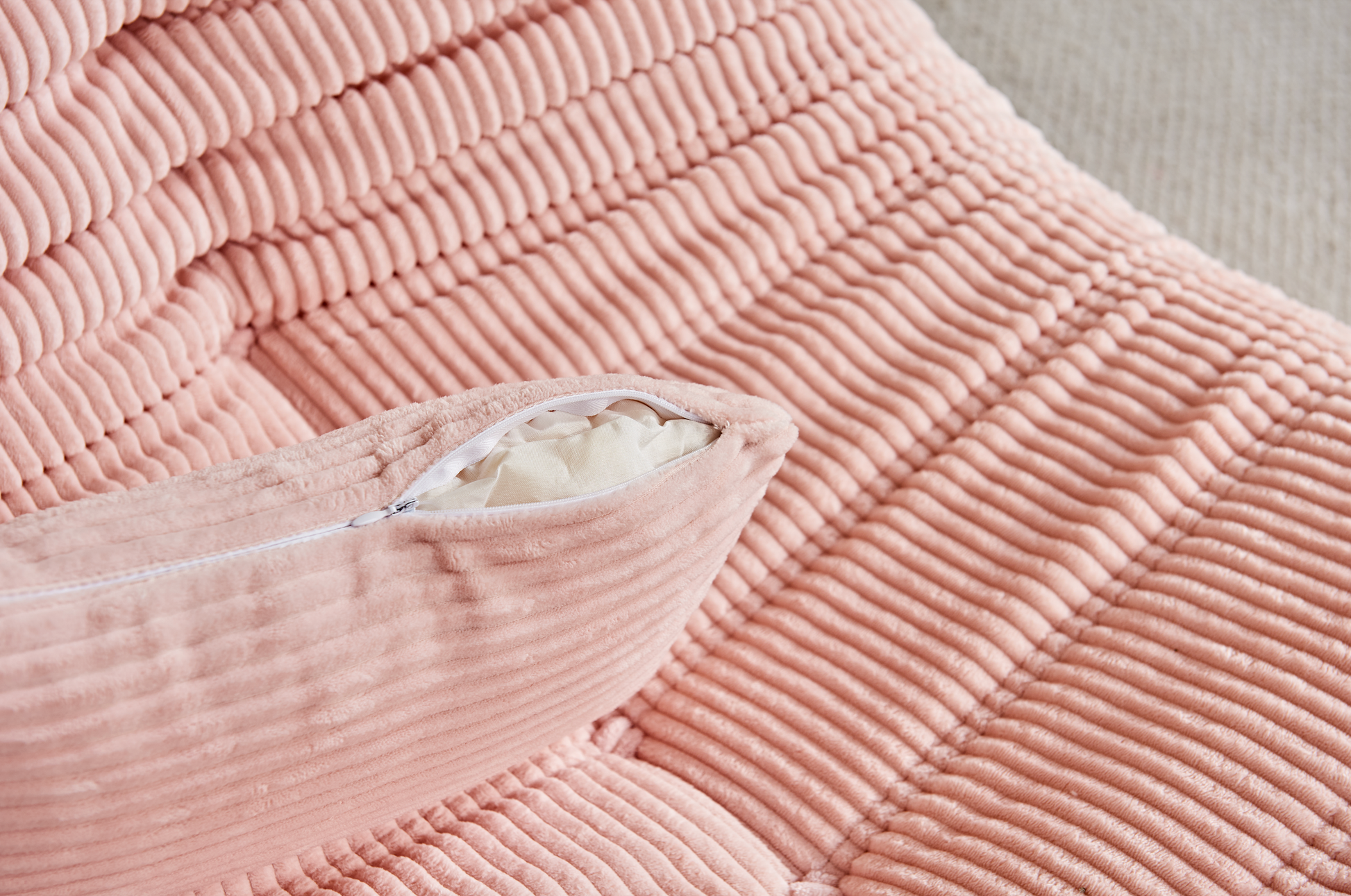 Close-up of Zoovee's pink corduroy bean bag chair with a pillow inside, on a light background.